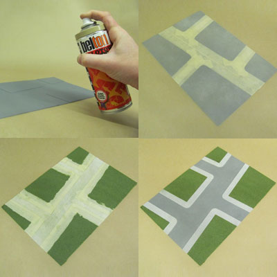 A finished card model of a road crossing with grey tarmac, pale pavements and green grass