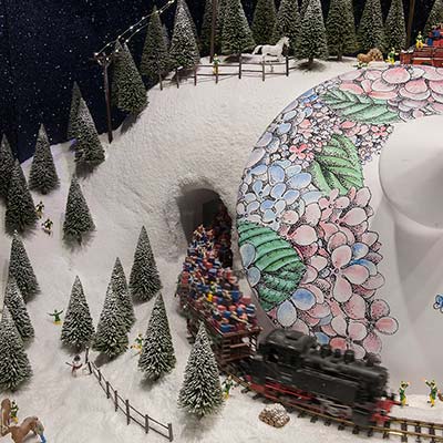 A model barn and fir trees covered in snow beside a railway track