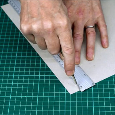 A cutting mat with a metal safety rule, a scalpel, a craft knife and a utility knife