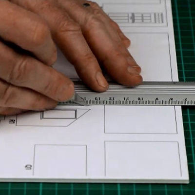 A cutting mat with a metal safety rule, a scalpel, a craft knife and a utility knife