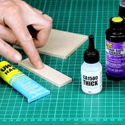 Bottles of PVA and superglue beside a balsa joint on a cutting mat