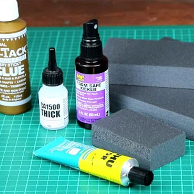 Bottles of PVA, superglue and accelerator with a tube of UHU POR beside blocks of grey Styrofoam