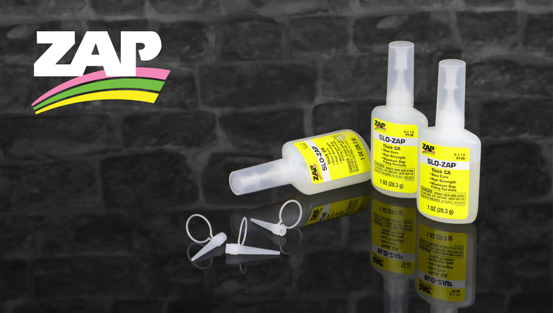 Zap and Slo-Zap glue bottles with applicator tips against a slate wall