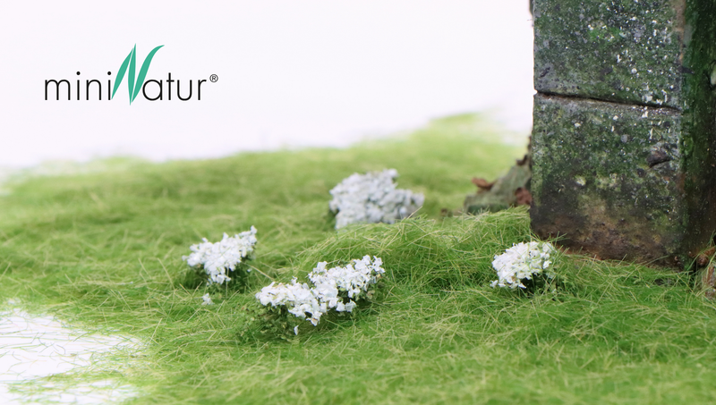 miniNatur static grass and white flowers at the base of a mossy stone